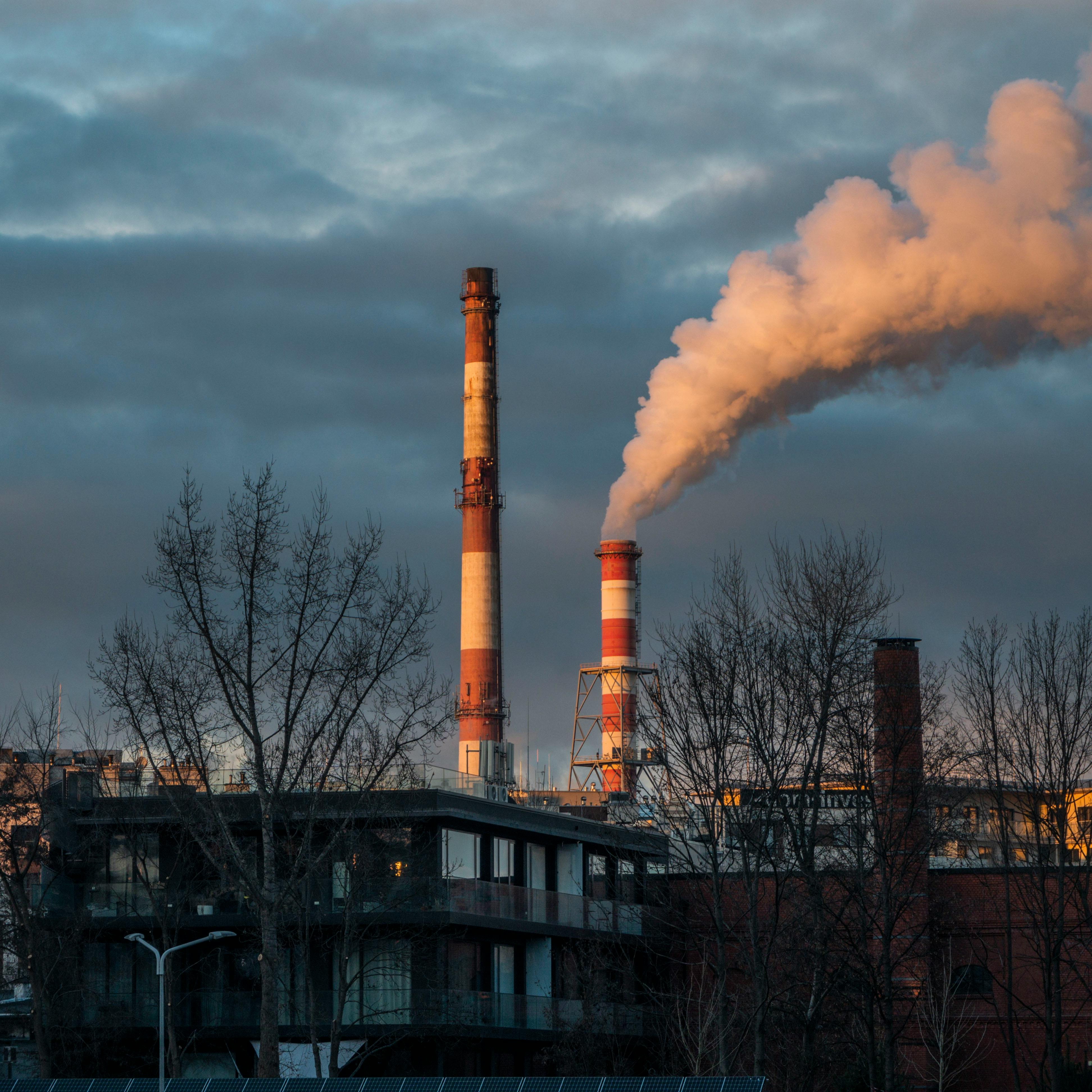 View of industrial chimneys releasing smoke in Wrocław during a cloudy evening.